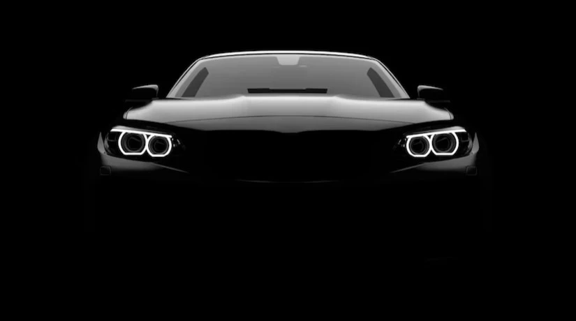 Vista frontal de un coche negro con los faros encendidos